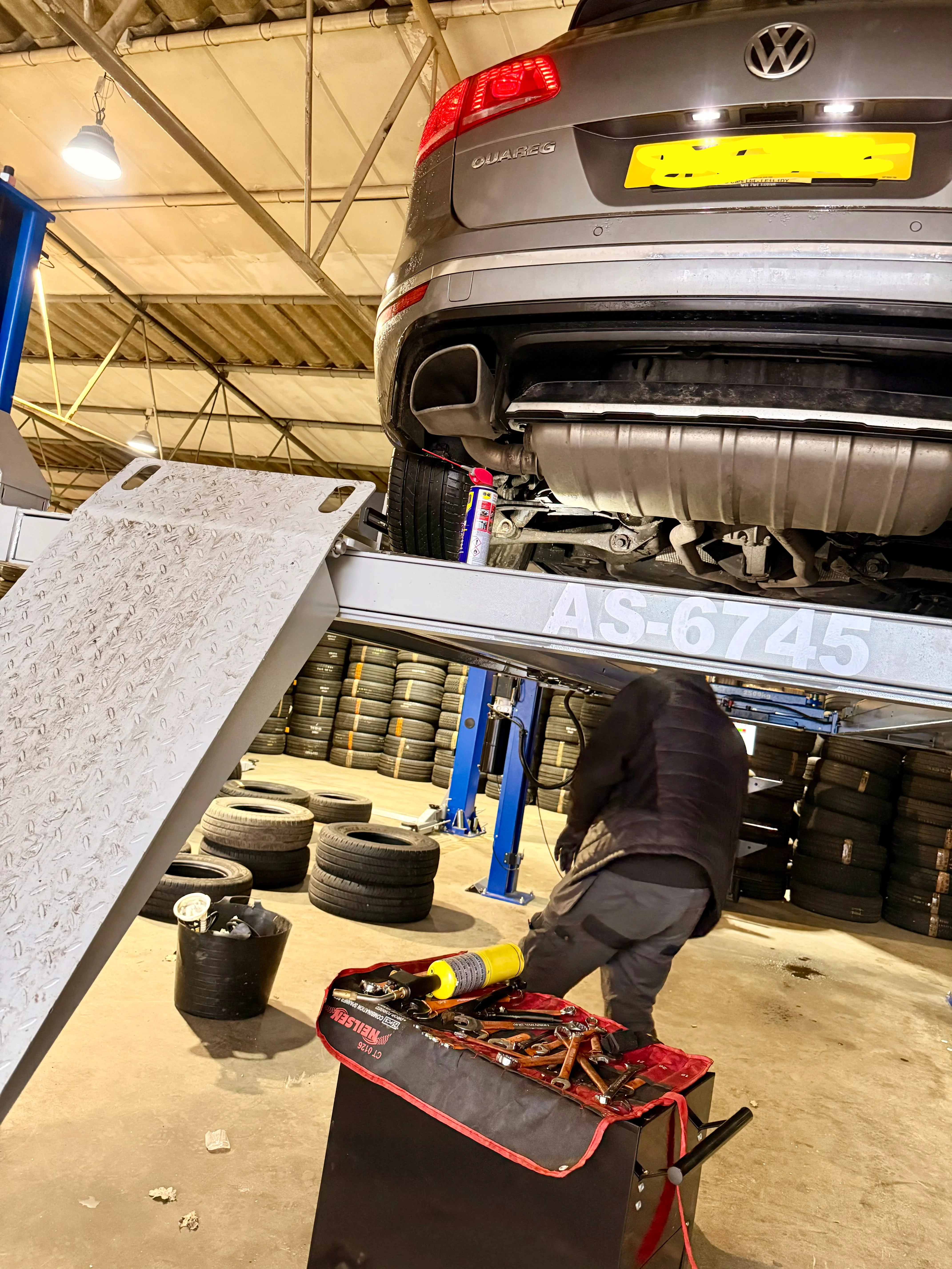 A ford pikcup on a ramp inside a garage.