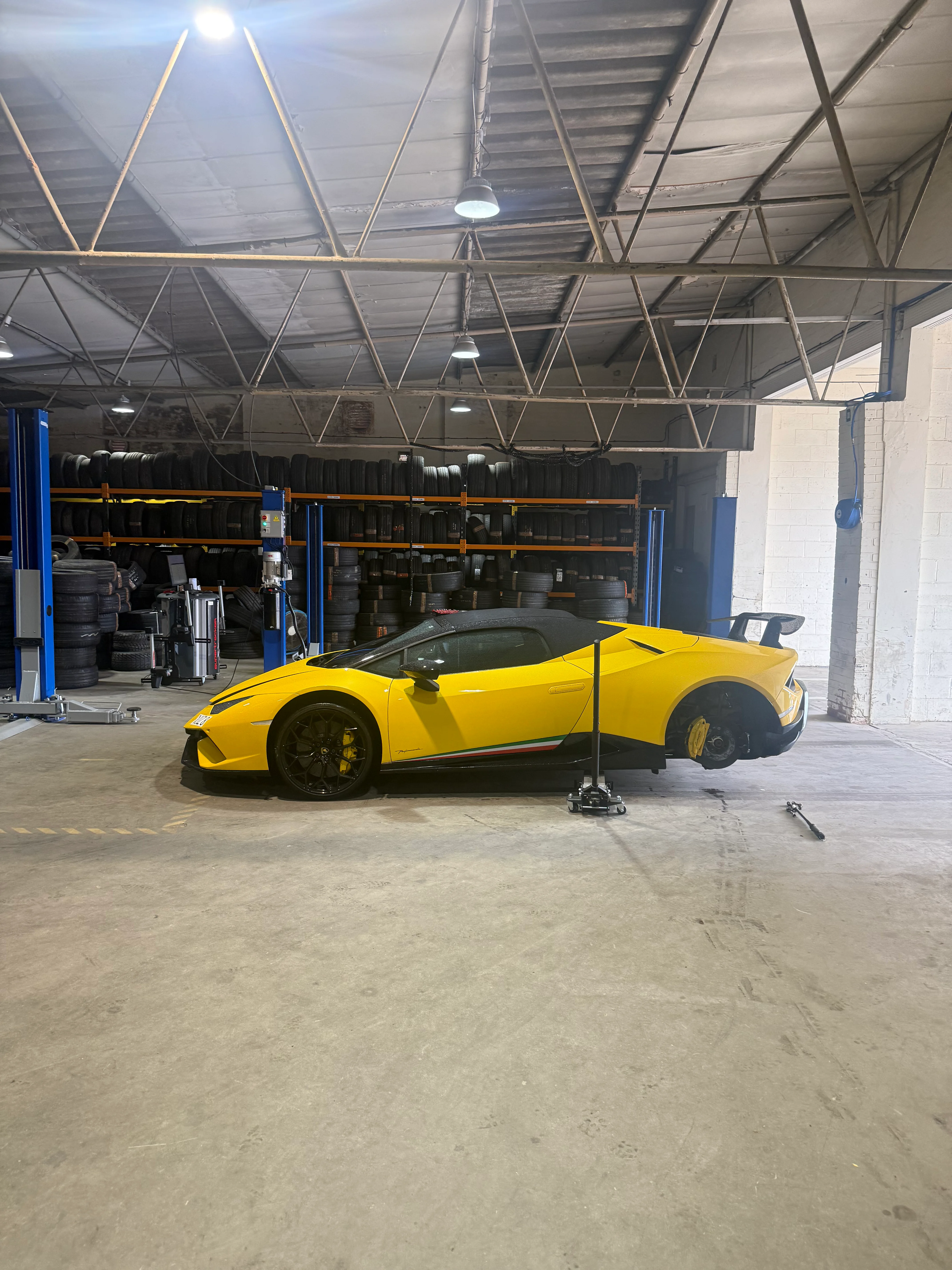 A yellow lamborghini on a ramp inside a garage.