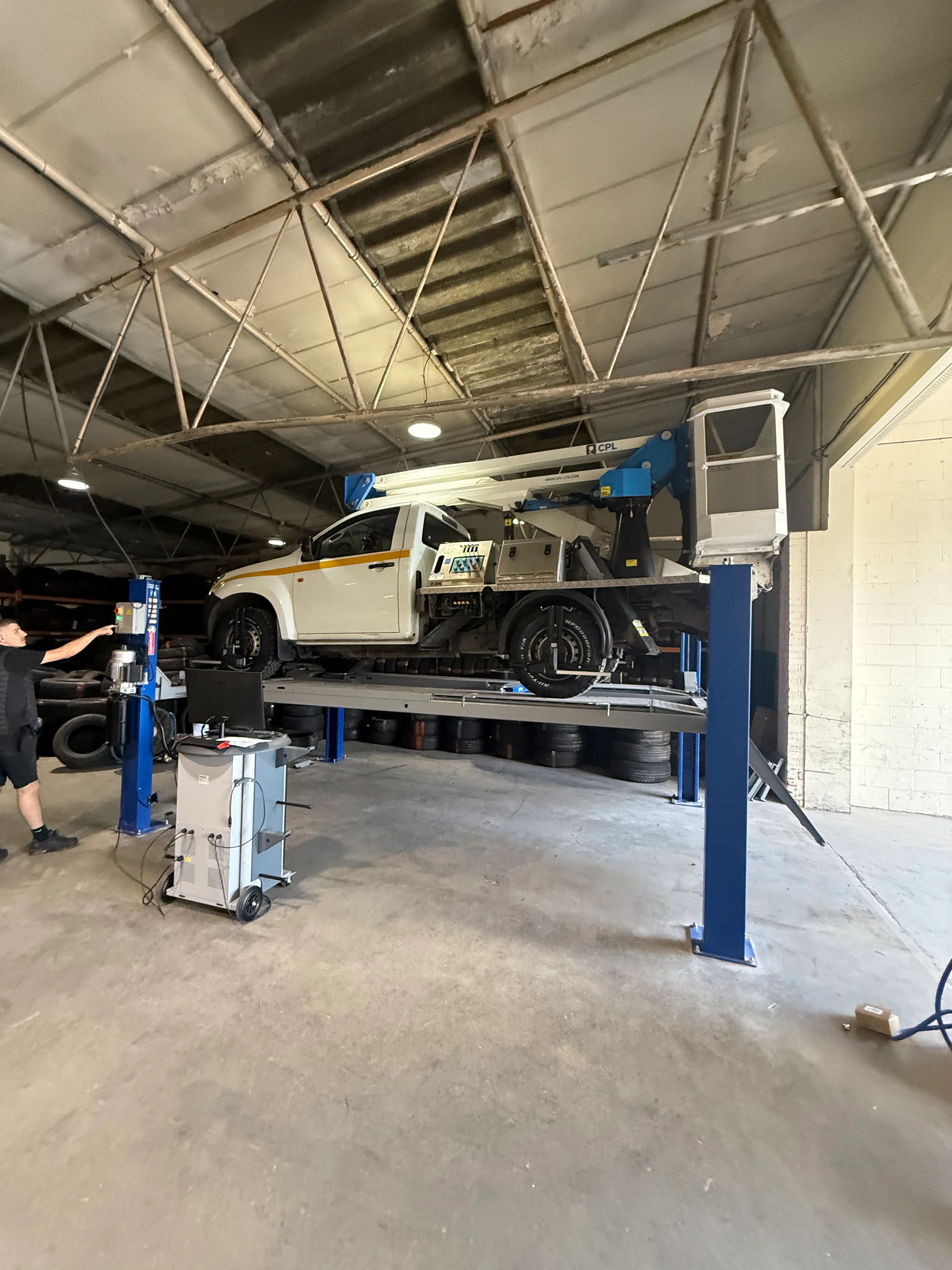 A ford pikcup on a ramp inside a garage.